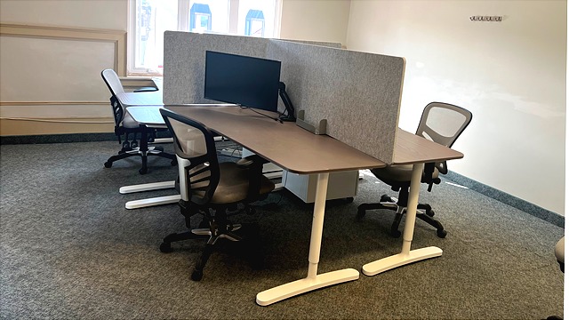 Professional hot desk setup at Route 93 Innovation Hub featuring privacy dividers, monitors, and ergonomic seating.